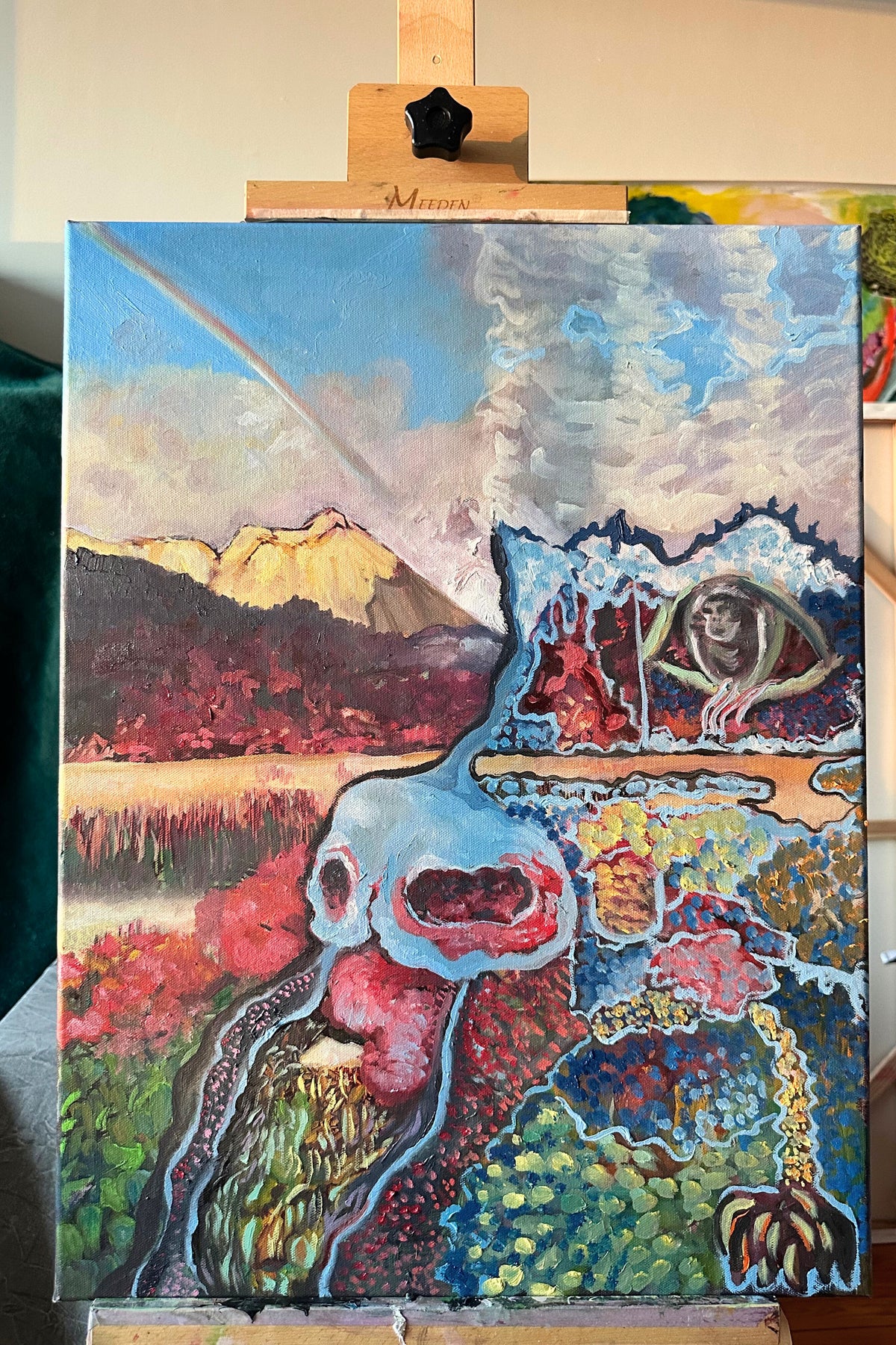 Colorful abstract painting on an easel with a mountain and nature elements.