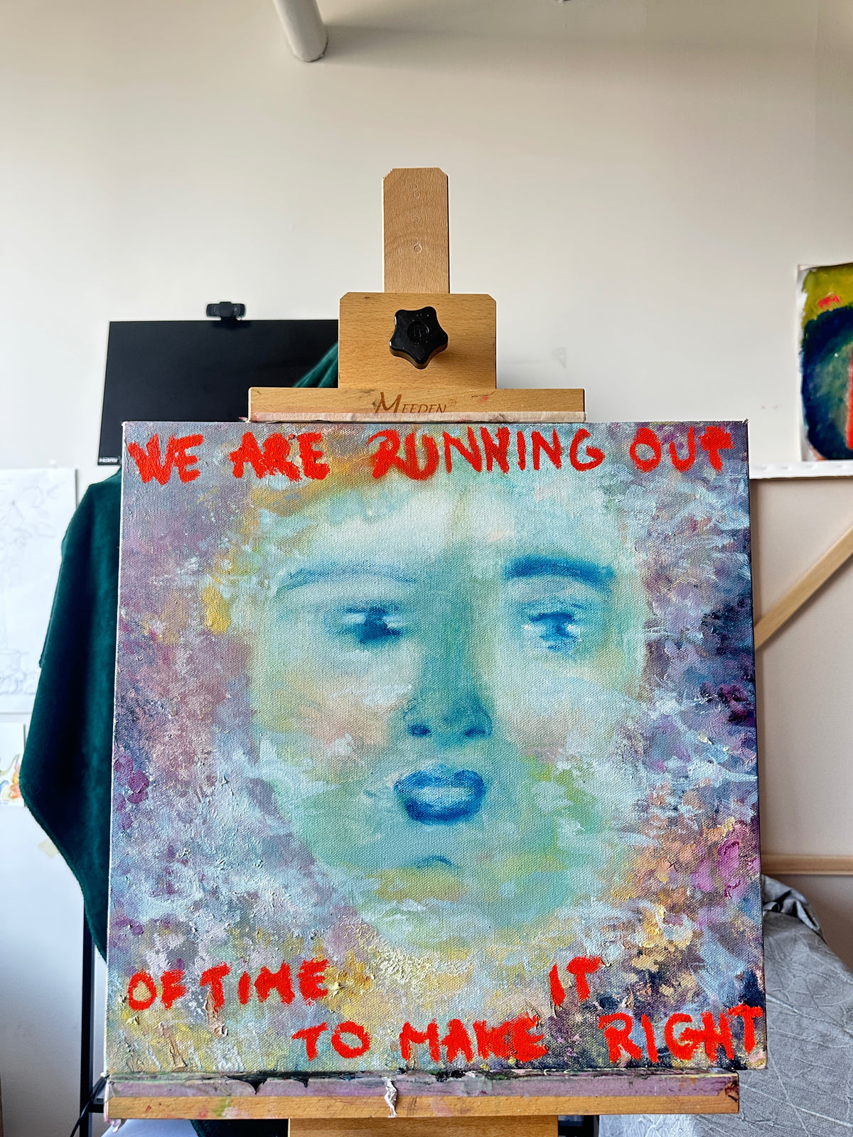 Artistic depiction of a face on an easel with text 'WE ARE RUNNING OUT OF TIME TO MAKE RIGHT' in a studio setting.