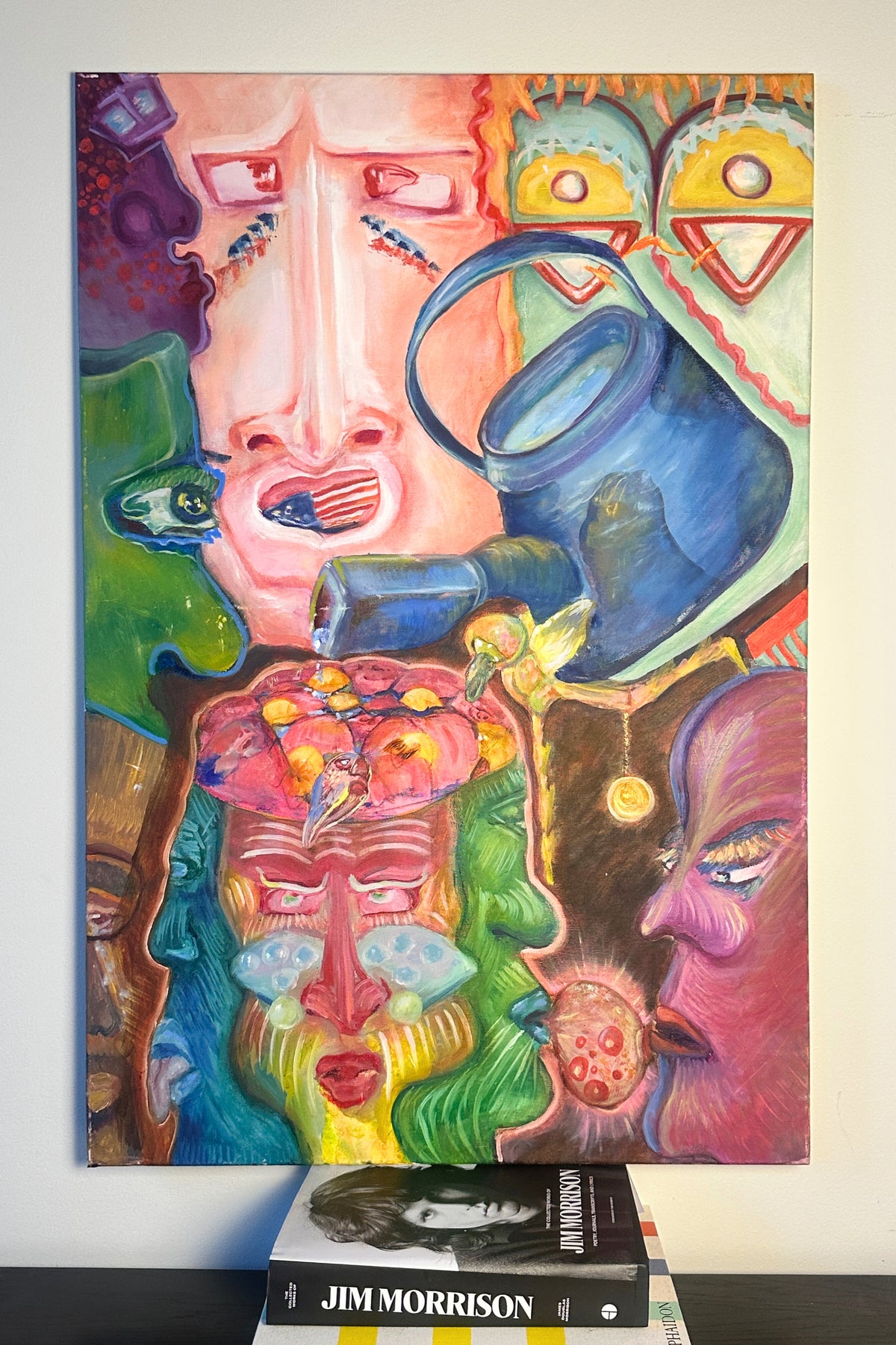 Colorful abstract artwork with faces and objects on a white wall.