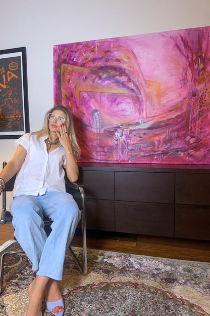 Woman sitting in a chair in front of a large abstract painting in a room.